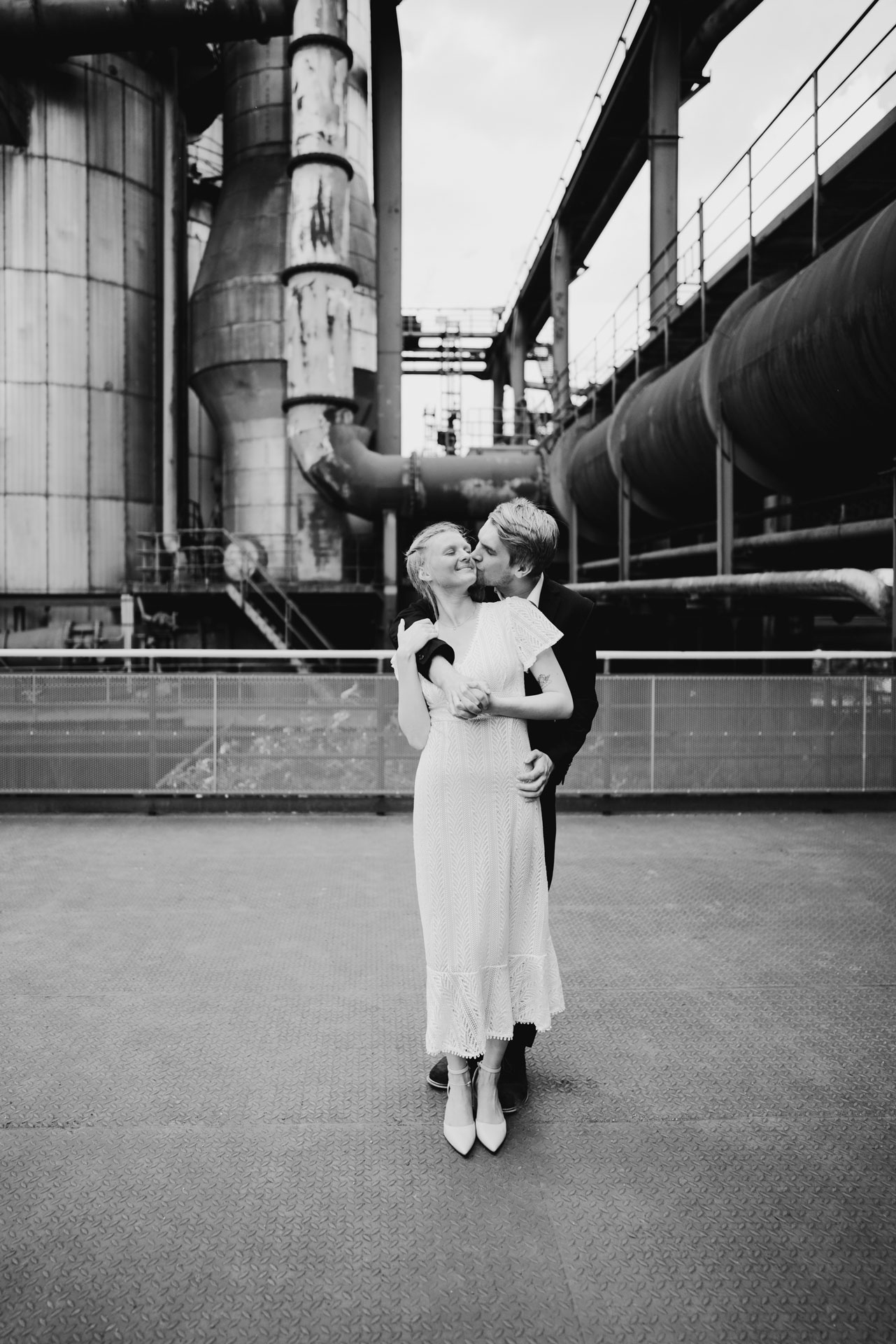 Engagementshooting im Landschaftspark Nord, Duisburg: Verliebtes Paar in inniger Umarmung vor Industrieruine - Fotograf: Sugata Tyler